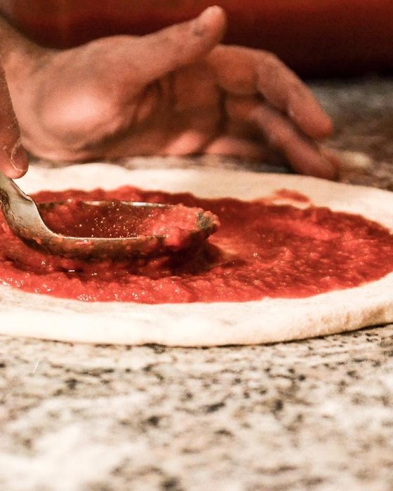 Il pomodoro steso col cucchiaio sul disco di pasta